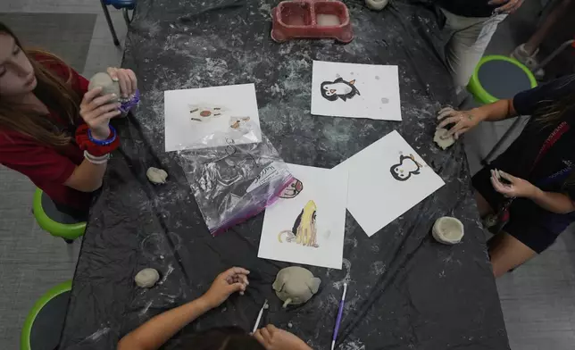 Ella Oliveri, 8, left, works alongside third grade classmates to sculpt clay models of endangered or vulnerable animal species, in Lindsey Wuest's Science As Art class, at A.D. Henderson School in Boca Raton, Fla., Tuesday, April 16, 2024. (AP Photo/Rebecca Blackwell)