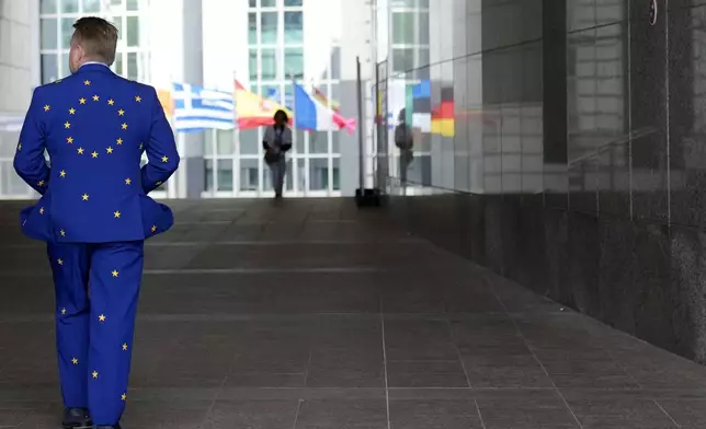 FILE - A man wears a suit in the EU colors as he walks outside the European Parliament during Europe Day celebrations in Brussels on May 4, 2024. The European Union marks Europe Day on Thursday, May 9, but instead of the traditionally muted celebrations, all eyes are on the EU elections in one month time which portend a steep rise of the extreme right and a possible move away from its global trendsetting climate policies. (AP Photo/Virginia Mayo, File)