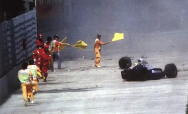 FILE- Race officials run toward Brazil's Aytron Senna after he crashed with his Williams-Renault during the San Marino F-1 Grand Prix in Imola Sunday May 1, 1994. The 30th anniversary of Ayrton Senna’s death is commemorated on Wednesday, May 1, 2024, with a memorial on the Imola track where he crashed during the 1994 San Marino Grand Prix. (AP Photo/File)