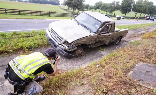 Highway Patrol Cpl. Brett Detweiler takes pictures of the pick up truck that was involved in the crash scene as emergency workers worked the scene of a fatal bus crash carrying laborers that overturned Tuesday morning, May 14, 2024, in Ocala, Fla. (Doug Engle/Ocala Star-Banner via AP)
