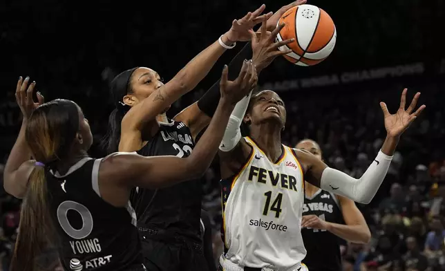 From left, Las Vegas Aces guard Jackie Young (0), center A'ja Wilson (22) and Indiana Fever center Temi Fagbenle (14) vie for a rebound during the second half of a WNBA basketball game Saturday, May 25, 2024, in Las Vegas. (AP Photo/John Locher)