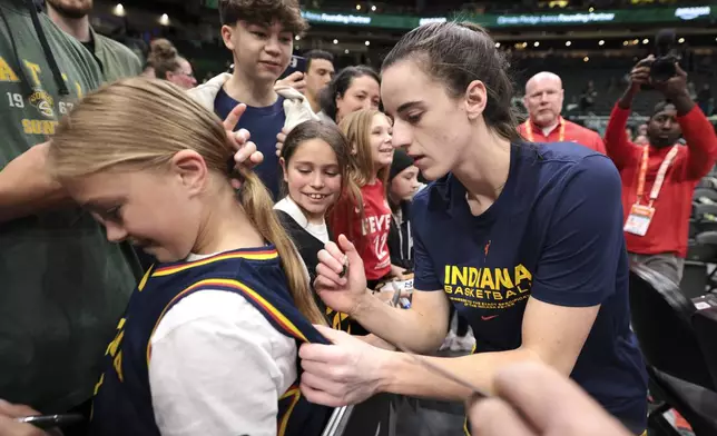 Indiana Fever guard Caitlin Clark, right, signs autographs before the team's WNBA basketball game against the Seattle Storm, Wednesday, May 22, 2024, in Seattle. (AP Photo/Jason Redmond)