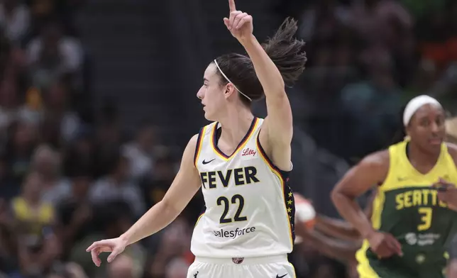 Indiana Fever guard Caitlin Clark (22) points downcourt as Seattle Storm forward Nneka Ogwumike (3) runs nearby during the first half of a WNBA basketball game Wednesday, May 22, 2024, in Seattle. (AP Photo/Jason Redmond)