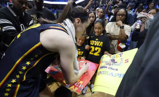 Indiana Fever guard Caitlyn Clark, left, signs autographs for Iowa fans after Indiana lost to the Dallas Wings during an WNBA basketball game in Arlington, Texas, Friday, May 3, 2024. (AP Photo/Michael Ainsworth)