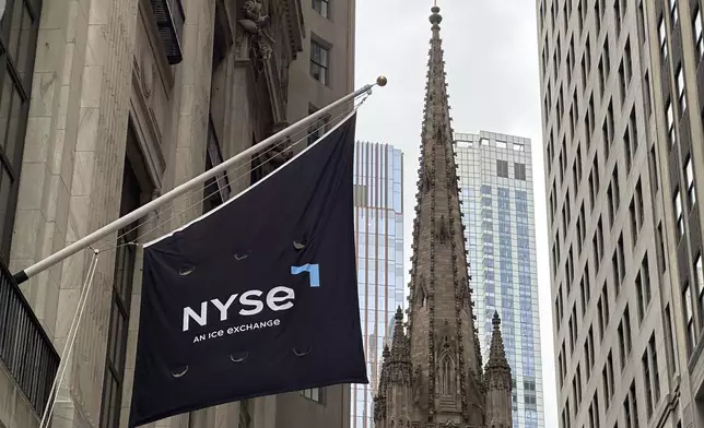 FILE - A flag hangs from the side of the New York Stock Exchange is on Thursday, May 16, 2024, in New York. Trinity Church appears in the background. (AP Photo/Peter Morgan, File)
