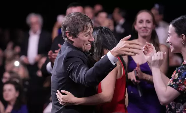 Sean Baker, centre, is embraced prior to accepting the Palme d'Or for the film 'Anora,' during the awards ceremony of the 77th international film festival, Cannes, southern France, Saturday, May 25, 2024 (Photo by Andreea Alexandru/Invision/AP)