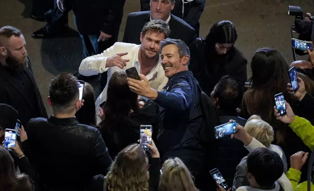 Chris Hemsworth, left centre, poses for a selfie upon departure from the premiere of the film 'Furiosa: A Mad Max Saga' at the 77th international film festival, Cannes, southern France, Wednesday, May 15, 2024. (Photo by Andreea Alexandru/Invision/AP)