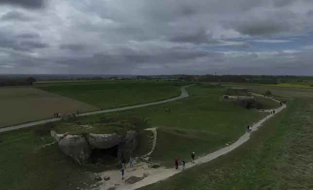 People walk by a bunker in Longues-sur-Mer, Normandy, Thursday, April 11, 2024. On D-Day, Charles Shay was a 19-year-old Native American army medic who was ready to give his life — and actually saved many. Now 99, he's spreading a message of peace with tireless dedication as he's about to take part in the 80th celebrations of the landings in Normandy that led to the liberation of France and Europe from Nazi Germany occupation. (AP Photo/Thibault Camus)