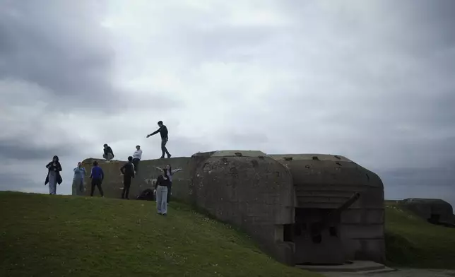 Students walk by a bunker in Longues-sur-Mer, Normandy, Thursday, April 11, 2024. On D-Day, Charles Shay was a 19-year-old Native American army medic who was ready to give his life — and actually saved many. Now 99, he's spreading a message of peace with tireless dedication as he's about to take part in the 80th celebrations of the landings in Normandy that led to the liberation of France and Europe from Nazi Germany occupation. (AP Photo/Thibault Camus)