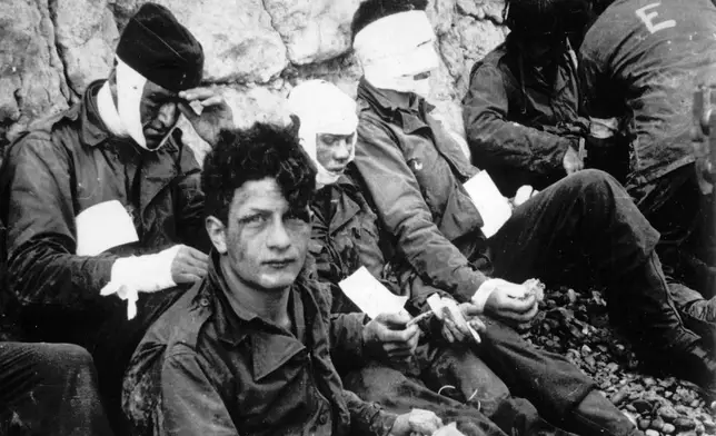 Men of the American assault troops of the 16th Infantry Regiment, injured while storming a coastal area code-named Omaha Beach during the Allied invasion of the Normandy, wait by the chalk cliffs at Collville-sur-Mer for evacuation to a field hospital for further treatment, June 6, 1944. On D-Day, Charles Shay was a 19-year-old Native American army medic who was ready to give his life — and actually saved many. Now 99, he's spreading a message of peace with tireless dedication as he's about to take part in the 80th celebrations of the landings in Normandy that led to the liberation of France and Europe from Nazi Germany occupation. (AP Photo, File)