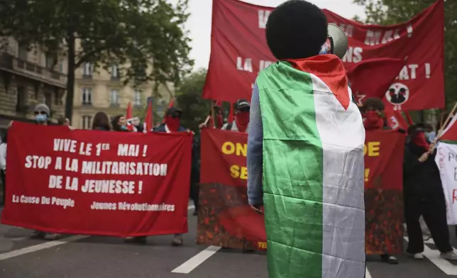 A protester wrapped in a Palestinian flag attends the May Day demonstration, Wednesday, May 1, 2024 in Paris. (AP Photo/Thomas Padilla)