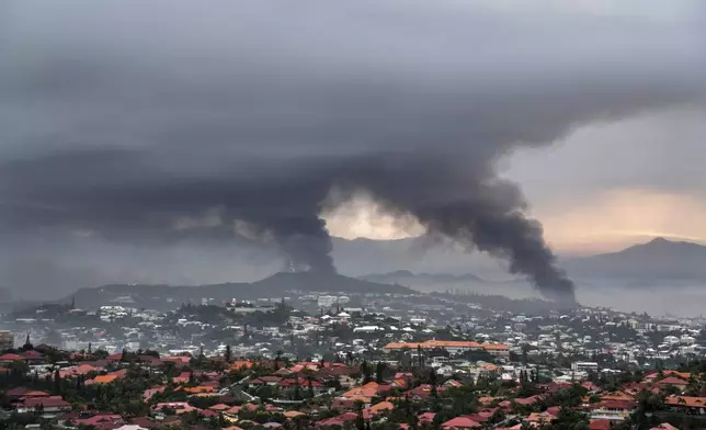 FILE - Smoke rises during protests in Noumea, New Caledonia, Wednesday May 15, 2024. Using backhoes to shove aside charred vehicles, French security forces worked Sunday, May 19, 2024, to retake control of the highway to the international airport in violence-scorched New Caledonia, shuttered because of deadly unrest wracking the French South Pacific island where indigenous people have long sought independence from France. (AP Photo/Nicolas Job, File)