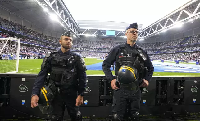 French riot police officers stand on the side of the pitch watching the crowd before the French Cup final soccer match between Lyon and PSG at the Pierre Mauroy stadium in Villeneuve d'Ascq, northern France, Saturday, May 25, 2024. (AP Photo/Michel Euler)