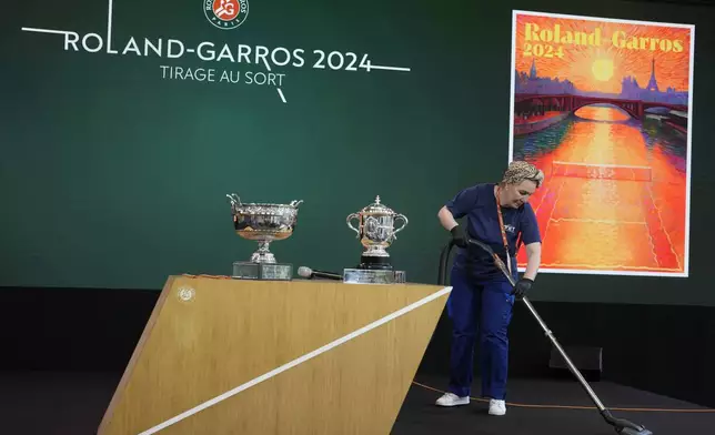 A woman cleans the stage before the draw for the French Tennis Open at the Roland Garros stadium, Thursday, May 23, 2024 in Paris. The tournament starts Sunday May 26, 2024. (AP Photo/Thibault Camus)