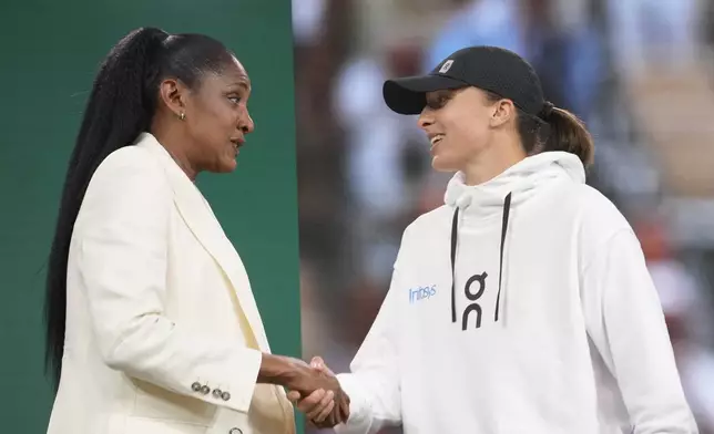 Former French athletic champion Marie-Jose Perec, left, shakes hands with French Open titleholder Poland's Iga Swiatek during the draw for the French Tennis Open at the Roland Garros stadium, Thursday, May 23, 2024 in Paris. The tournament starts Sunday May 26, 2024. (AP Photo/Thibault Camus)