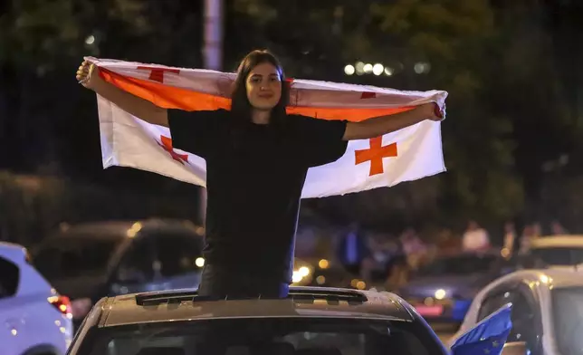 A demonstrator holds a Georgian national flag during an opposition protest against "the Russian law" in the center of Tbilisi, Georgia, on Thursday, May 2, 2024. The parliament of Georgia has cancelled its plenary session following massive protests against a proposed law that critics fear will stifle media freedom and endanger the country's bid for membership in the European Union. (AP Photo/Zurab Tsertsvadze)