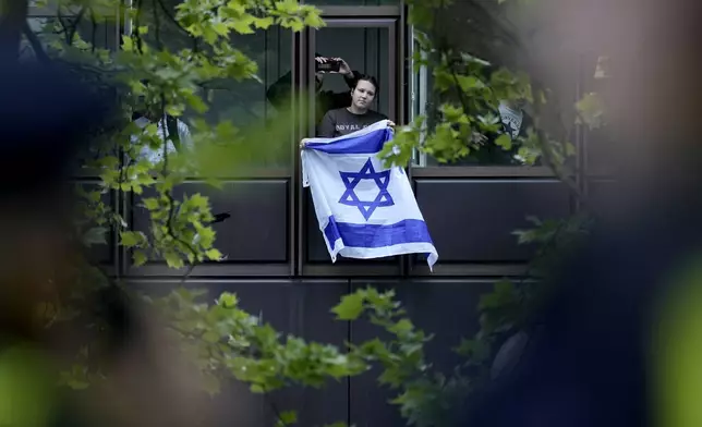 A man shows an Israeli flag during a pro-Palestinians demonstration by the group "Student Coalition Berlin" in the theater courtyard of the 'Freie Universität Berlin' university in Berlin, Germany, Tuesday, May 7, 2024. Pro-Palestinian activists occupied a courtyard of the Free University in Berlin on Tuesday. (AP Photo/Markus Schreiber)