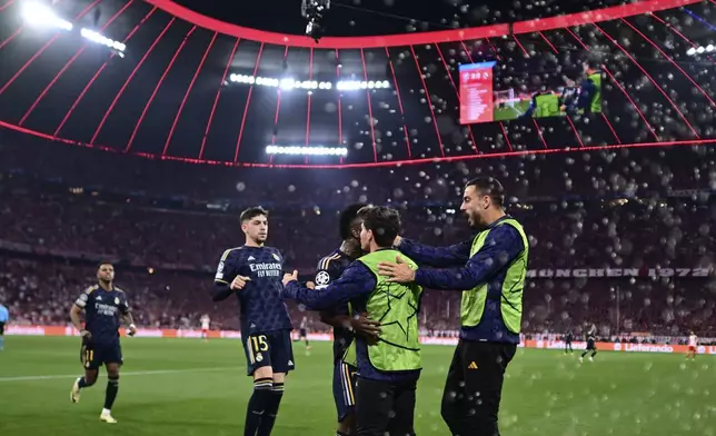 Real Madrid's Vinicius Junior, centre, celebrates with his teammates after scoring his side's second goal on a penalty kick during the Champions League semifinal first leg soccer match between Bayern Munich and Real Madrid at the Allianz Arena in Munich, Germany, Tuesday, April 30, 2024. (AP Photo/Christian Bruna)