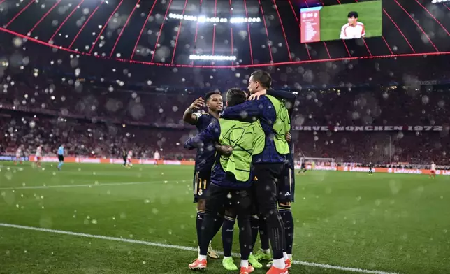 Real Madrid's Vinicius Junior, covered by his teammates, celebrates after scoring his side's second goal on a penalty kick during the Champions League semifinal first leg soccer match between Bayern Munich and Real Madrid at the Allianz Arena in Munich, Germany, Tuesday, April 30, 2024. (AP Photo/Christian Bruna)