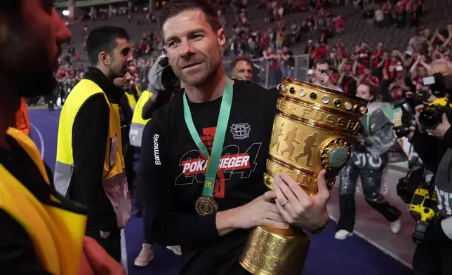 Leverkusen's head coach Xabi Alonso lifts the trophy after the German Soccer Cup final match between 1. FC Kaiserslautern and Bayer Leverkusen at the Olympic Stadium in Berlin, Germany, Saturday, May 25, 2024. (AP Photo/Matthias Schrader)