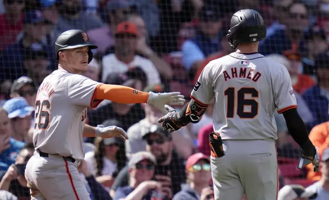 San Francisco Giants' Nick Ahmed (16) is congratulated by Matt Chapman, left, after his sacrifice, which scored Chapman, a during the seventh inning of a baseball game against the Boston Red Sox at Fenway Park, Thursday, May 2, 2024, in Boston. (AP Photo/Charles Krupa)