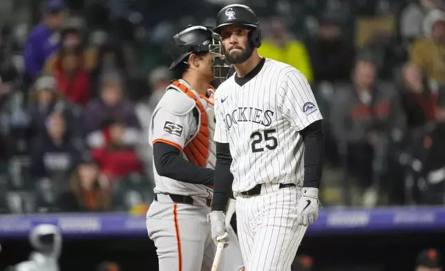 Colorado Rockies' Jacob Stallings, front, reacts after striking out against San Francisco Giants pitcher Camilo Doval as catcher Blake Sabol waits for play to resume in the ninth inning of a baseball game Tuesday, May 7, 2024, in Denver. (AP Photo/David Zalubowski)