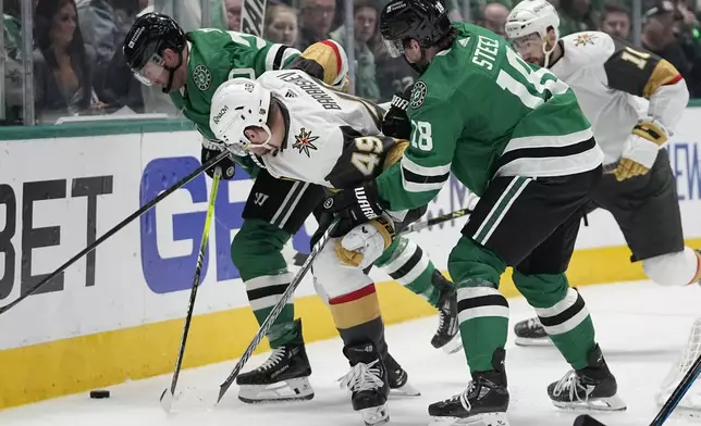 Dallas Stars' Ryan Suter, left, and Sam Steel (18) work to take control of the puck against Vegas Golden Knights' Ivan Barbashev (49) and Nicolas Roy (10) in t he second period in Game 5 of an NHL hockey Stanley Cup first-round playoff series in Dallas, Wednesday, May 1, 2024. (AP Photo/Tony Gutierrez)