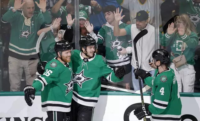 Dallas Stars center Wyatt Johnston, center, celebrates his first period goal with Joe Pavelski (16) and Miro Heiskanen (4) during Game 7 of an NHL hockey Stanley Cup first-round playoff series against the Vegas Golden Knights, Sunday, May 5, 2024, in Dallas. (AP Photo/Brandon Wade)