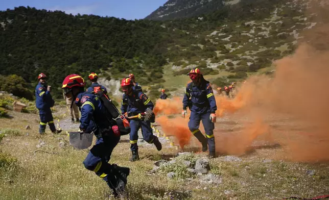 Firefighters of the 1st Wildfire Special Operation Unit, take part in a drill near Villia village some 60 kilometers (37 miles) northwest of Athens, Greece, Friday, April 19, 2024. Greece's fire season officially starts on May 1 but dozens of fires have already been put out over the past month after temperatures began hitting 30 degrees Celsius (86 degrees Fahrenheit) in late March. This year, Greece is doubling the number of firefighters in specialized units to some 1,300, adopting tactics from the United States to try and outflank fires with airborne units scrambled to build breaks in the predicted path of the flames. (AP Photo/Thanassis Stavrakis)