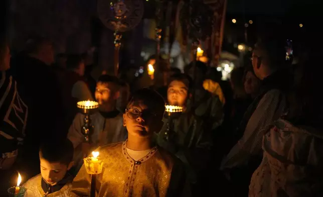 Altar boys take part in the procession of "Epitaphios", the bier that carries the body of Jesus Christ to his grave, at the Venetian port, in Nafpaktos town, western Greece, on Good Friday, May 3, 2024. The solemn processions in Greece, with the flower-adorned biers followed by the clergy and the faithful, are often spectacular, especially in places where bier processions from each parish converge into a central square. (AP Photo/Thanassis Stavrakis)