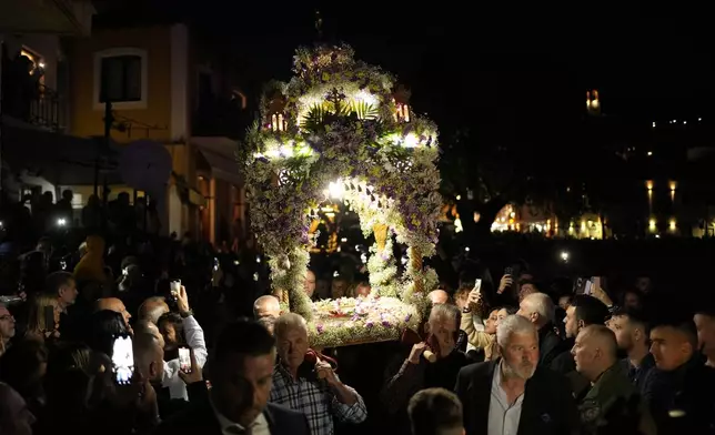 The procession of "Epitaphios", the bier that carries the body of Jesus Christ to his grave, arrives at the Venetian port, in Nafpaktos town, western Greece, on Good Friday, May 3, 2024. The solemn processions in Greece, with the flower-adorned biers followed by the clergy and the faithful, are often spectacular, especially in places where bier processions from each parish converge into a central square. (AP Photo/Thanassis Stavrakis)