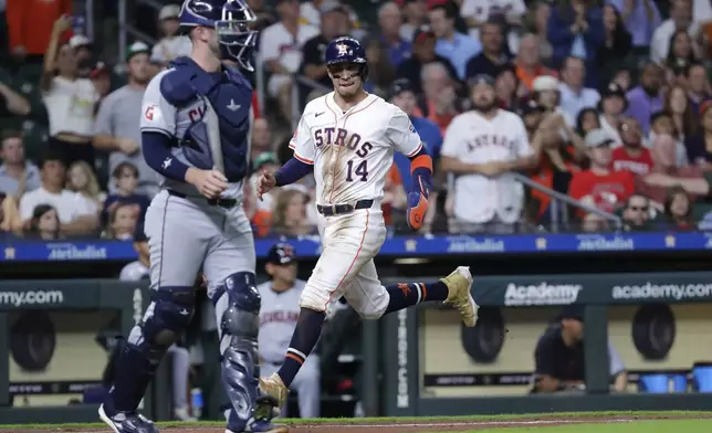 Houston Astros' Mauricio Dubon (14) scores behind Cleveland Guardians catcher David Fry, left, on the RBI single by Jose Altuve during the sixth inning of a baseball game Wednesday, May 1, 2024, in Houston. (AP Photo/Michael Wyke)