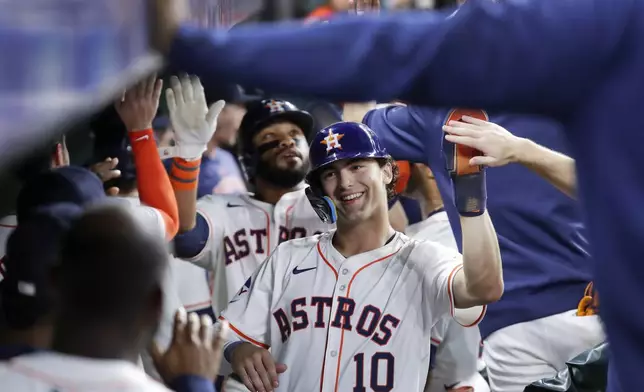 Houston Astros' Jon Singleton, left, and Joey Loperfido (10) collect high fives in the dugout after they both scored on the three run home run by Singleton against the Cleveland Guardians during the fourth inning of a baseball game Tuesday, April 30, 2024, in Houston. Loperfido batted in two run on his RBI single for his first major league hit just before Singleton's home run.(AP Photo/Michael Wyke)
