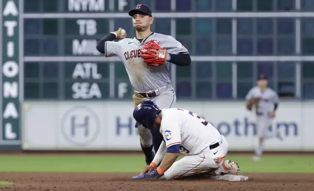 Cleveland Guardians second baseman Andres Gimenez, left, throws to first base on an attempted double play after making the out on Houston Astros' Jeremy Pena, right, during the ninth inning of a baseball game Wednesday, May 1, 2024, in Houston. (AP Photo/Michael Wyke)