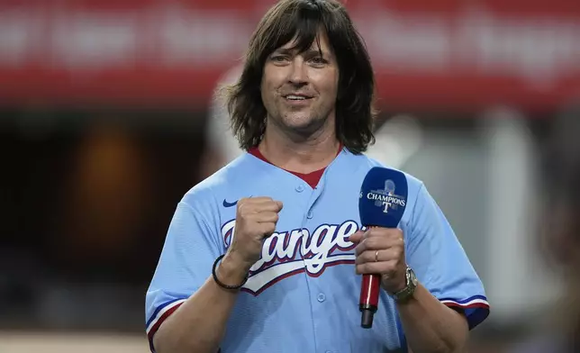 Rhett Miller reacts to applause after singing the national anthem before a baseball game between the Cleveland Guardians and Texas Rangers in Arlington, Texas, Wednesday, May 15, 2024. (AP Photo/LM Otero)