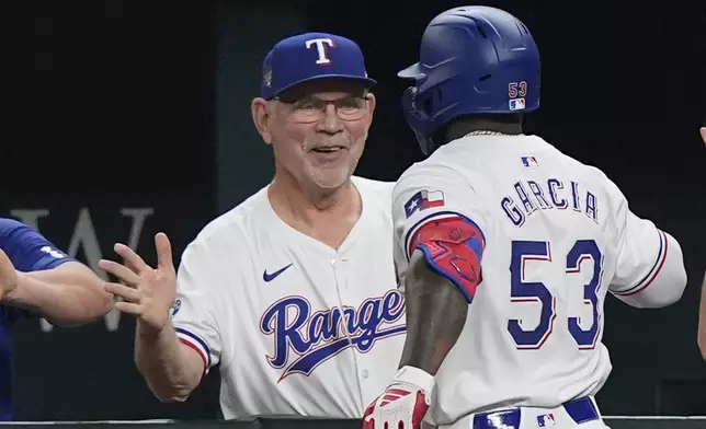 Texas Rangers manager Bruce Bochy, left, congratulates Adolis García (53) after he hit a home run that also scored teammate Jonah Heim during the sixth inning of a baseball game against the Cleveland Guardians in Arlington, Texas, Wednesday, May 15, 2024. (AP Photo/LM Otero)