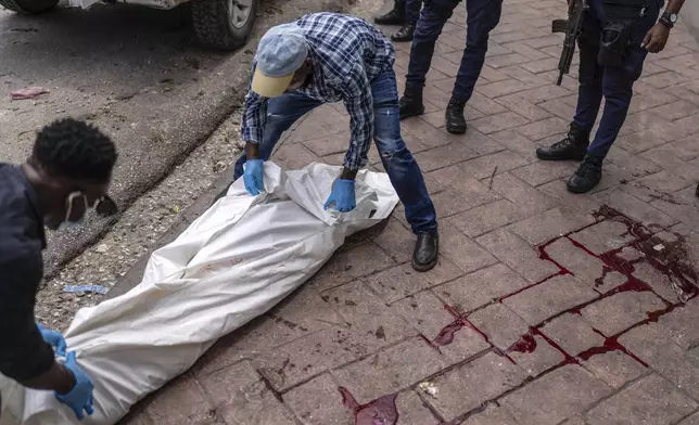 Forensic workers remove the body of a man shot dead in the Petion-Ville neighborhood of Port-au-Prince, Haiti, Friday, May 3, 2024. (AP Photo/Ramon Espinosa)