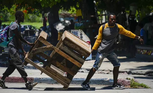 Street vendors move their booth after gunshots broke out near the National Palace in Port-au-Prince, Haiti, Tuesday, April 30, 2024. (AP Photo/Ramon Espinosa)