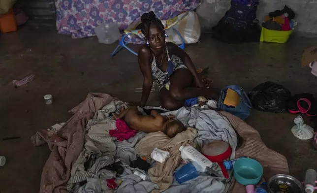 A woman sits next to her baby inside a classroom at a school converted into a makeshift shelter for people displaced by gang violence, in Port-au-Prince, Haiti, Wednesday, May 8, 2024. (AP Photo/Ramon Espinosa)