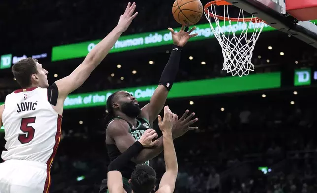Boston Celtics guard Jaylen Brown, center, drives to the basket against Miami Heat forward Nikola Jovic (5) and guard Tyler Herro during the first half of Game 5 of an NBA basketball first-round playoff series, Wednesday, May 1, 2024, in Boston. (AP Photo/Charles Krupa)