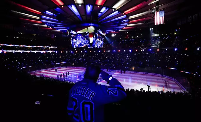 A New York Rangers fan salutes during the playing of the national anthem before Game 1 of an NHL hockey Stanley Cup second-round playoff series against the Carolina Hurricanes, Sunday, May 5, 2024, in New York. (AP Photo/Julia Nikhinson)