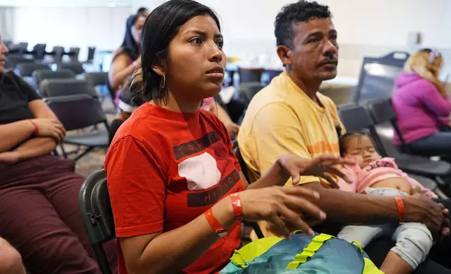 Brittany Gonzalez, front, speaks while her partner, Robinson San Juan, holds the couple's 1-year-old daughter, Triana Cataleya San Juan, during an orientation session for recent immigrants Monday, May 20, 2024, in Denver. (AP Photo/David Zalubowski)