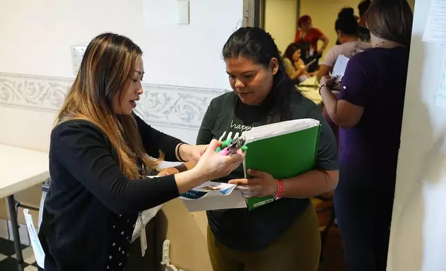 A volunteer checks in an attendee during an orientation session for recent immigrants, Monday, May 20, 2024, in Denver. (AP Photo/David Zalubowski)