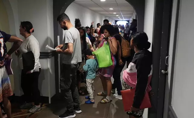 People queue up to enter an orientation session for recent immigrants, Monday, May 20, 2024, in Denver. (AP Photo/David Zalubowski)