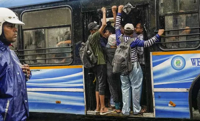 Commuters travel in a crowded bus in Kolkata, India, as rain continues after cyclone Remal made a landfall near Bangladesh-India border, Monday, May 27, 2024. (AP Photo/Bikas Das)