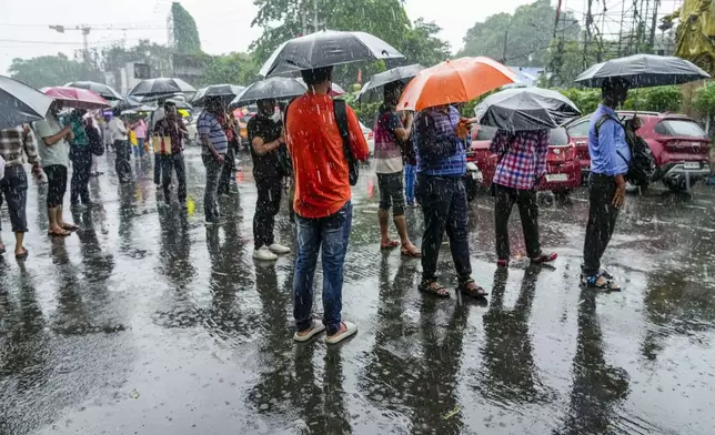 Stranded passengers await transport in Kolkata, India, as rain continues after cyclone Remal made a landfall near Bangladesh-India border, Monday, May 27, 2024. (AP Photo/Bikas Das)