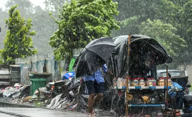 A commuter walks holding an umbrella in Kolkata, India, as rain continues after cyclone Remal made a landfall near Bangladesh-India border, Monday, May 27, 2024. (AP Photo/Bikas Das)