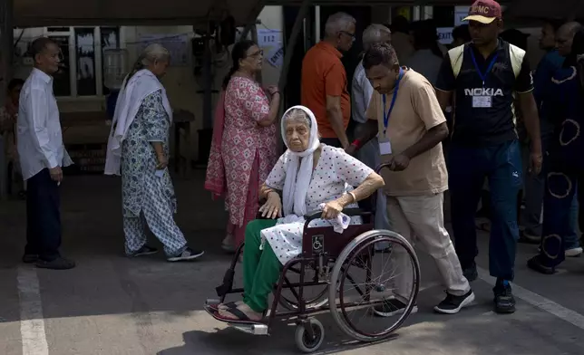 An elderly voter in a wheelchair shows her index finger marked with an indelible ink after she cast her vote in the sixth round of polling in India's national election in New Delhi, India, Saturday, May 25, 2024. (AP Photo/Altaf Qadri)