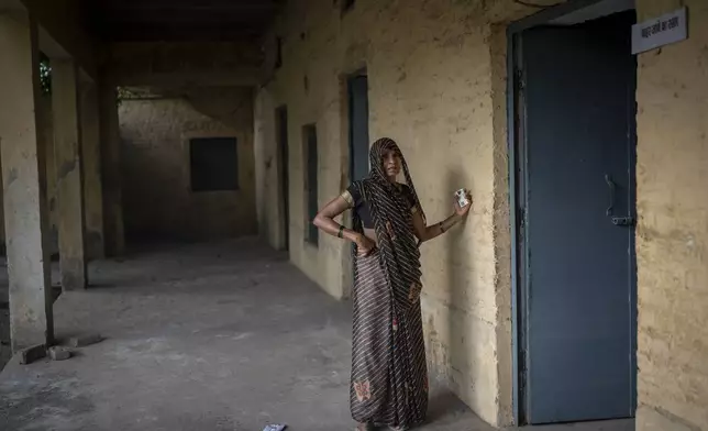 A woman waits at the door of a polling booth to cast her vote during the third round of voting in the six-week-long general election in Agra, Uttar Pradesh, India, Tuesday, May 7, 2024. (AP Photo/Altaf Qadri)