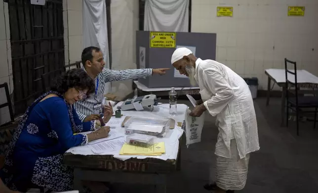 A Muslim voter is directed by a polling official as he registers to cast his vote in the sixth round of polling in India's national election in New Delhi, India, Saturday, May 25, 2024. (AP Photo/Altaf Qadri)